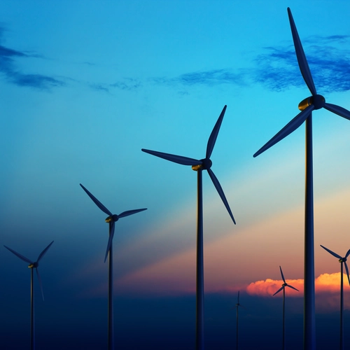Image of wind farm turbines against a sunset sky 